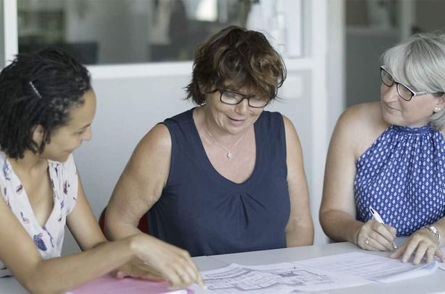 Photo de trois personnes autour d'un plan d'architecte